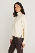 Gia Sweater in Pearl side view showing the ribbed hem and side slit on the ivory turtleneck