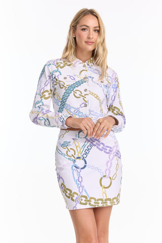 A woman wears the Monaco Denim Jacket - Chain Print (Preorder), a collared, long-sleeve, cropped jacket featuring blue, gold, and purple chain patterns, standing against a white background.