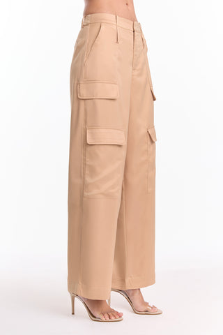 A person wearing the Milan Satin Cargo Pant in gold—a versatile trouser with large side pockets—paired with nude high-heeled sandals, stands against a plain white background.