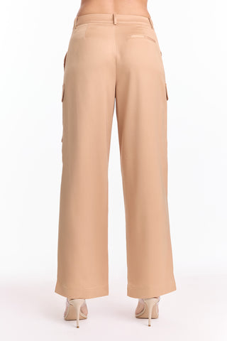 A person wearing the Milan Satin Cargo Pant - Gold (Preorder) shown from the back in a high-waisted, wide-leg satin-like gold fabric with nude heels against a plain white background.
