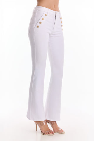A person wears the Allegra Bootcut Jean in white, featuring high waist and gold-buttoned front pockets, paired with clear high-heeled sandals, posed against a plain white background.