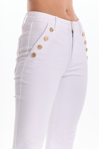 A close-up of a person wearing the Allegra Bootcut Jean - White, featuring a high waist and gold decorative buttons near the pockets, standing against a plain white background.