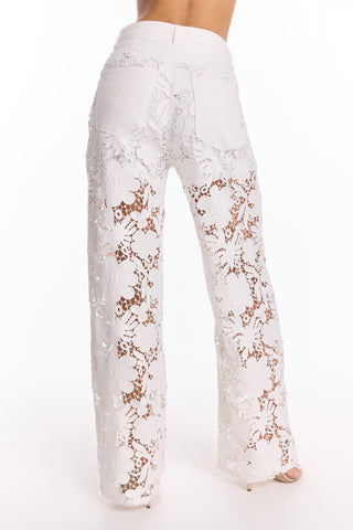 Wearing the Celeste Crochet Jean - White (Preorder), these high-waisted pants feature white floral lace with see-through legs and a solid upper section, creating a flattering silhouette and pocket coverage.