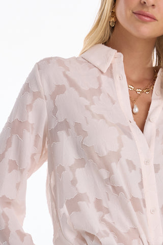 A woman wears the Stelle Button Up - Pearl, a lightweight lace blouse with a collar, paired with gold jewelry—a pearl pendant necklace and drop earrings. Only her lower face and torso are visible.