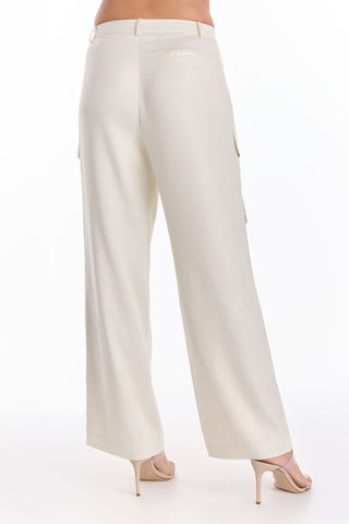 A person wearing the Milan Satin Cargo Pant in Pearl, a mid-rise and loose-fit silky satin pant, paired with beige high-heeled shoes, shown from the back against a white background.