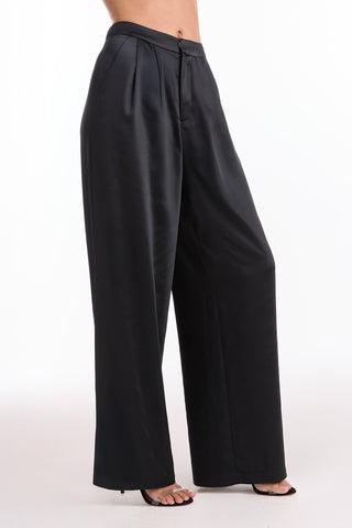 A person wears the Valentina Satin Pant - Black in a high-waist, wide-leg style with black open-toe heels, photographed against a plain white background.