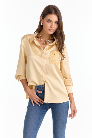 A woman poses with one hand in her pocket, wearing the Amelia Silky Lace Blouse - Butter Yellow (Preorder) with lace pocket detail, blue jeans, and a chunky gold necklace against a white background.