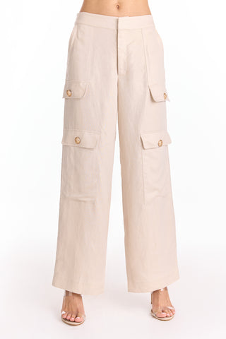 A person wears the Milan Linen Shimmer Cargo Pant - Gilded Beige (Preorder) with large front and side pockets, styled with open-toe heeled sandals. The mid-rise, wide-leg silhouette stands out on a plain white background.