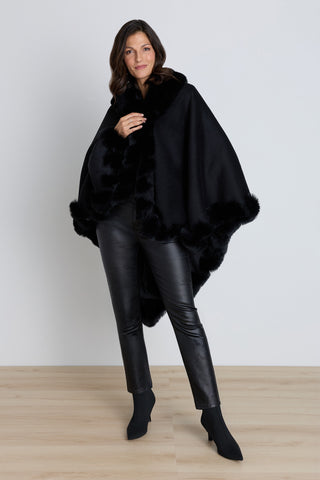 Woman wearing the Ophelia faux fur trim cape in black, front view