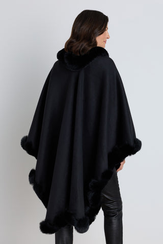 Woman styling the Ophelia black faux fur trim cape over an evening outfit