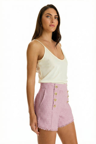 A woman in a white shirt and the Tamara Tweed Button Short - Blush with a gold side zipper, perfect for warm-weather dressing.