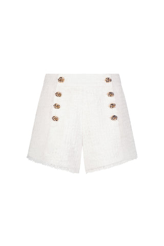 The Tamara Tweed Button Short - White is high-waisted with four decorative gold buttons per side, a gold side zipper, and frayed hems—ideal for chic warm-weather looks, shown against a plain white background.