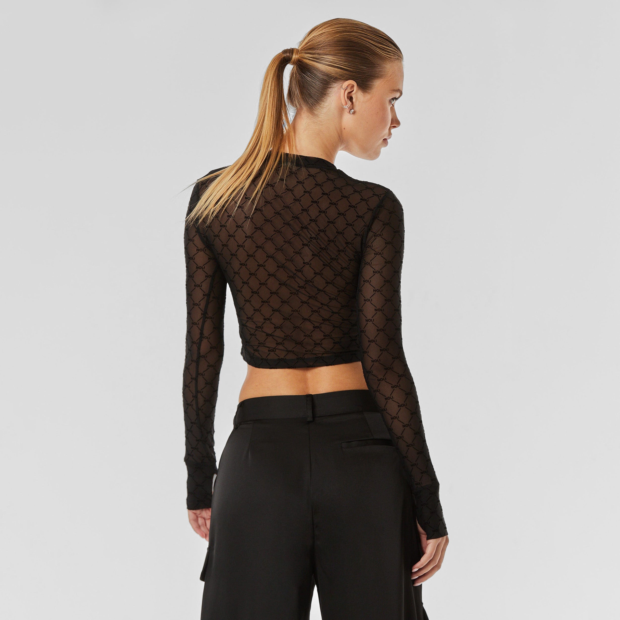 Rear view of woman wearing top featuring our ultra-soft and comfortable NOLI monogram flocked mesh topped with a slim fit and thumbholes