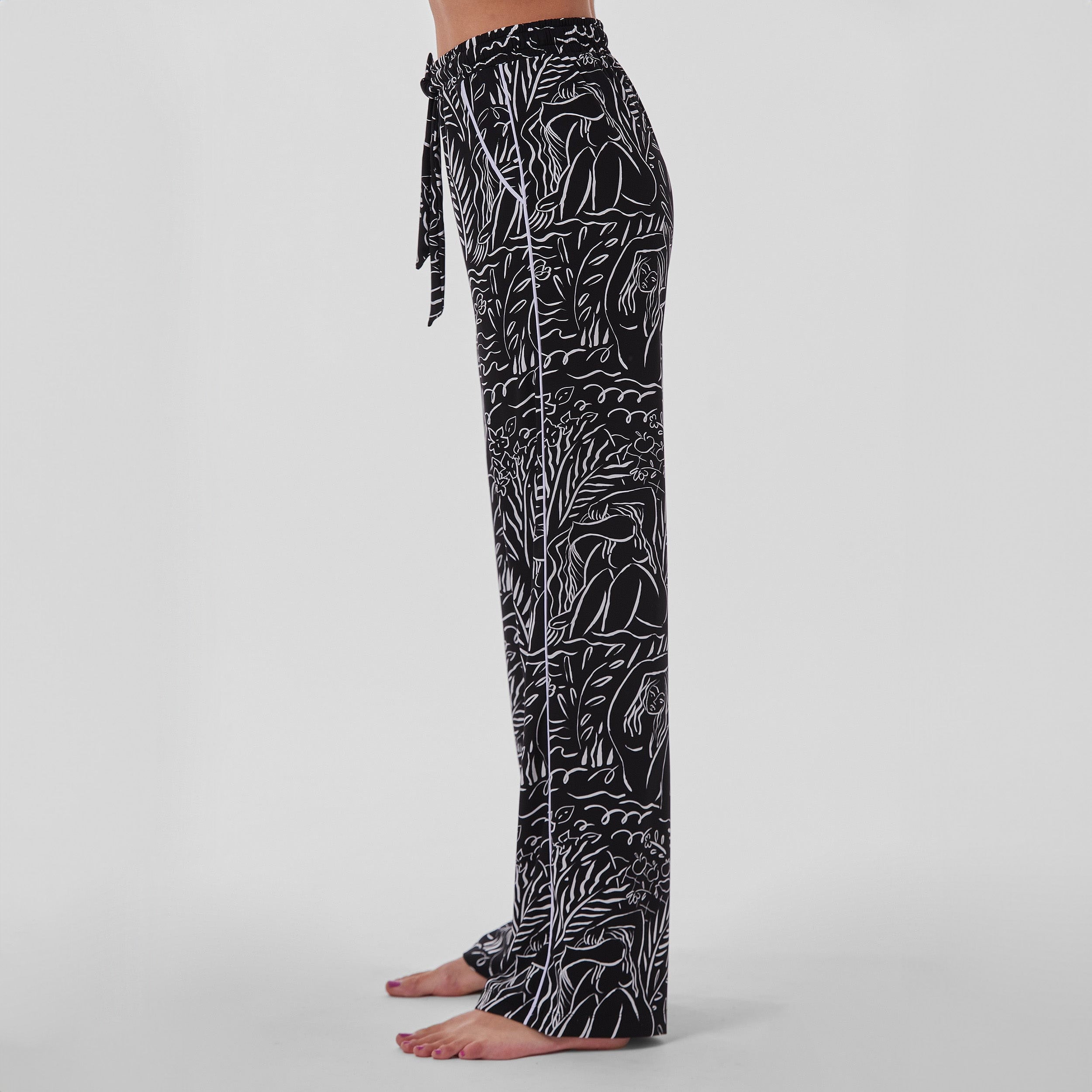 Side view of woman wearing breathable, relaxed and buttery smooth pajama pant featuring high-waist cut, side pockets, front tie and stunning Venus print.