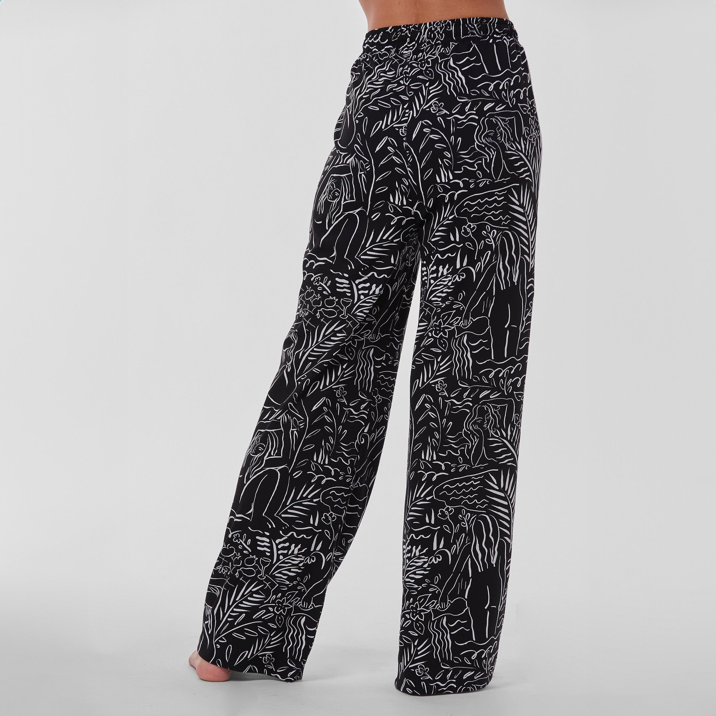 Rear view of woman wearing breathable, relaxed and buttery smooth pajama pant featuring high-waist cut, side pockets, front tie and stunning Venus print.