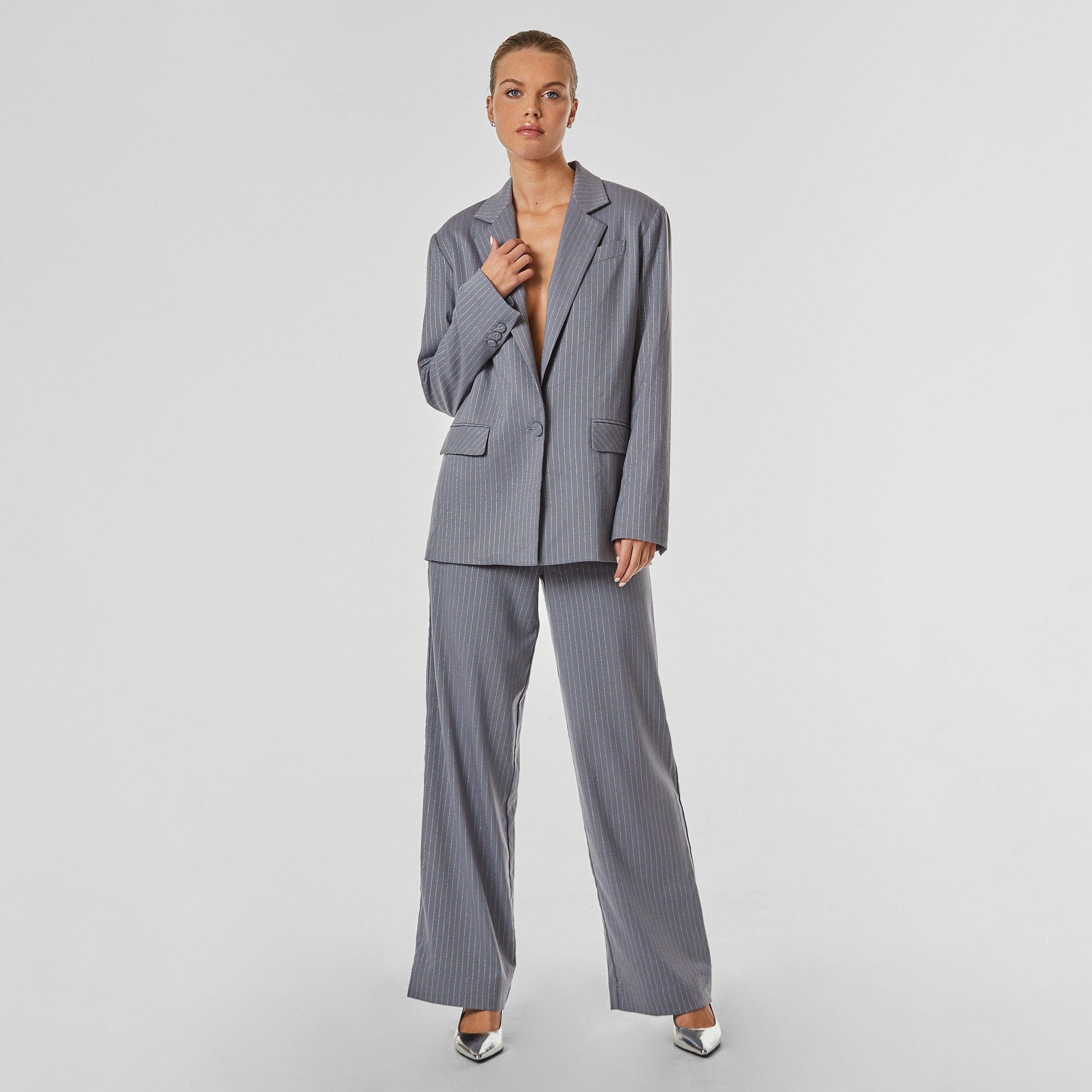Full view of woman wearing silver pinstripe on grey trouser with oversized fit