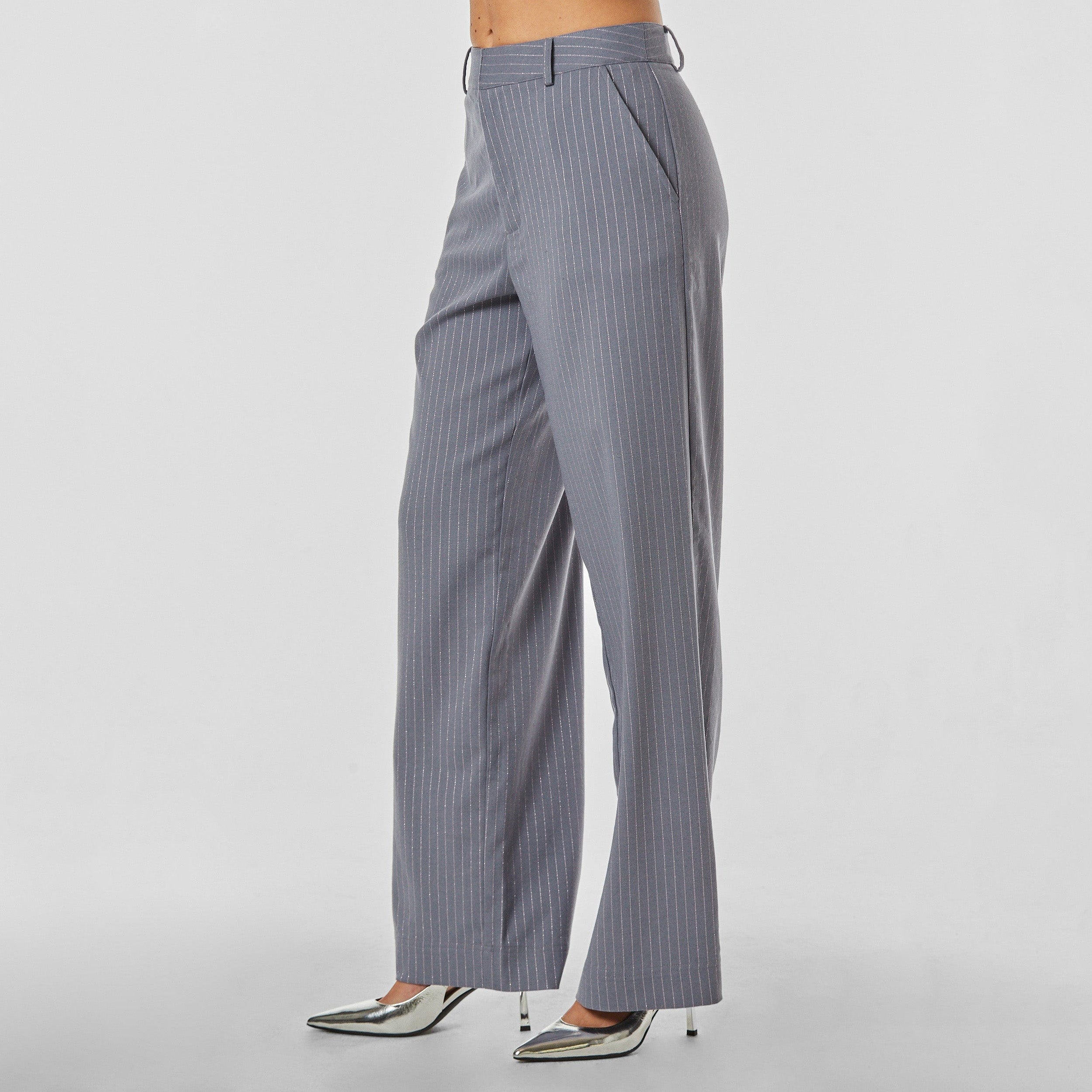 Side view of woman wearing silver pinstripe on grey trouser with oversized fit
